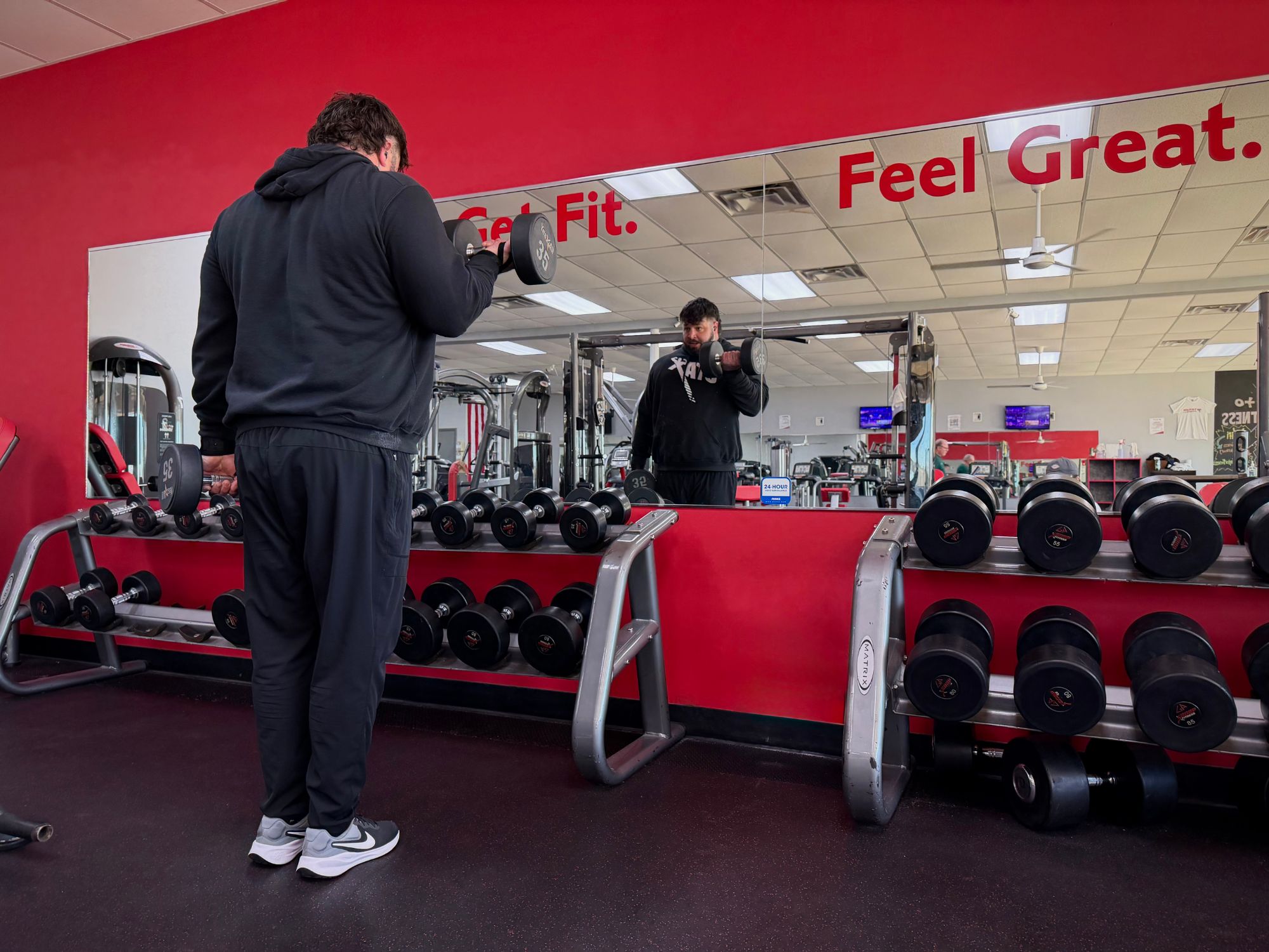 A member doing dumbbell curls in front of the Get Fit. Feel Great. mirror