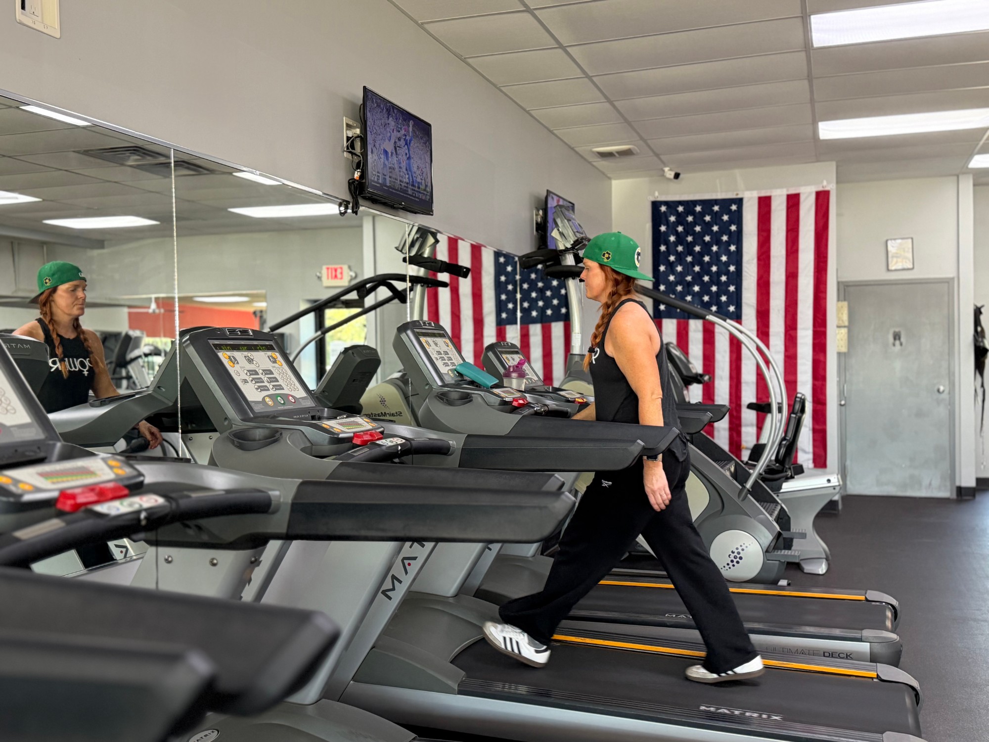 A member walking on a treadmill beside an American flag